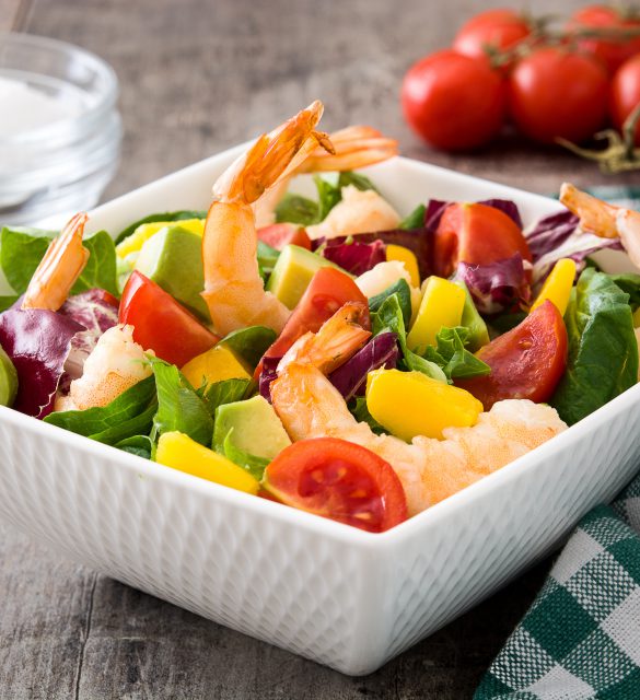 Shrimps salad with mango and avocado on wooden table