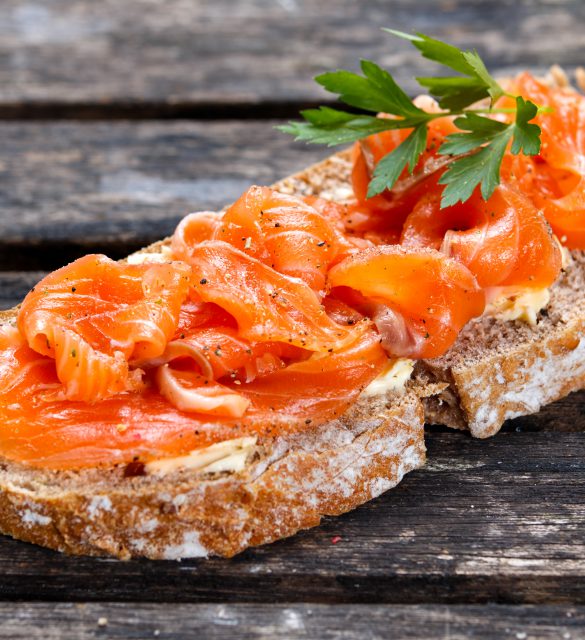 Fresh homemade sandwich with salmon on old wooden table.