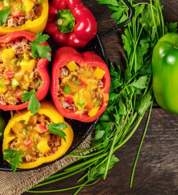 An overhead photo of stuffed bell peppers with fresh parsley and a green pepper, with a place for text