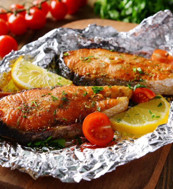 Tasty baked fish in foil on table close-up