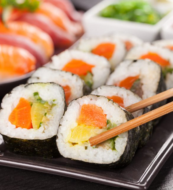 sushi pieces served on black stone with chopsticks