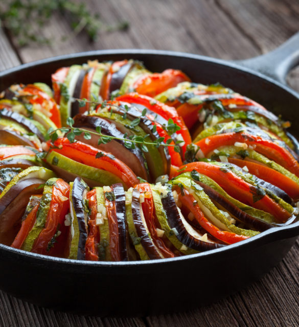 Traditional homemade vegetable ratatouille baked in cast iron frying pan healthy diet french vegetarian food on vintage wooden table background. Rustic style